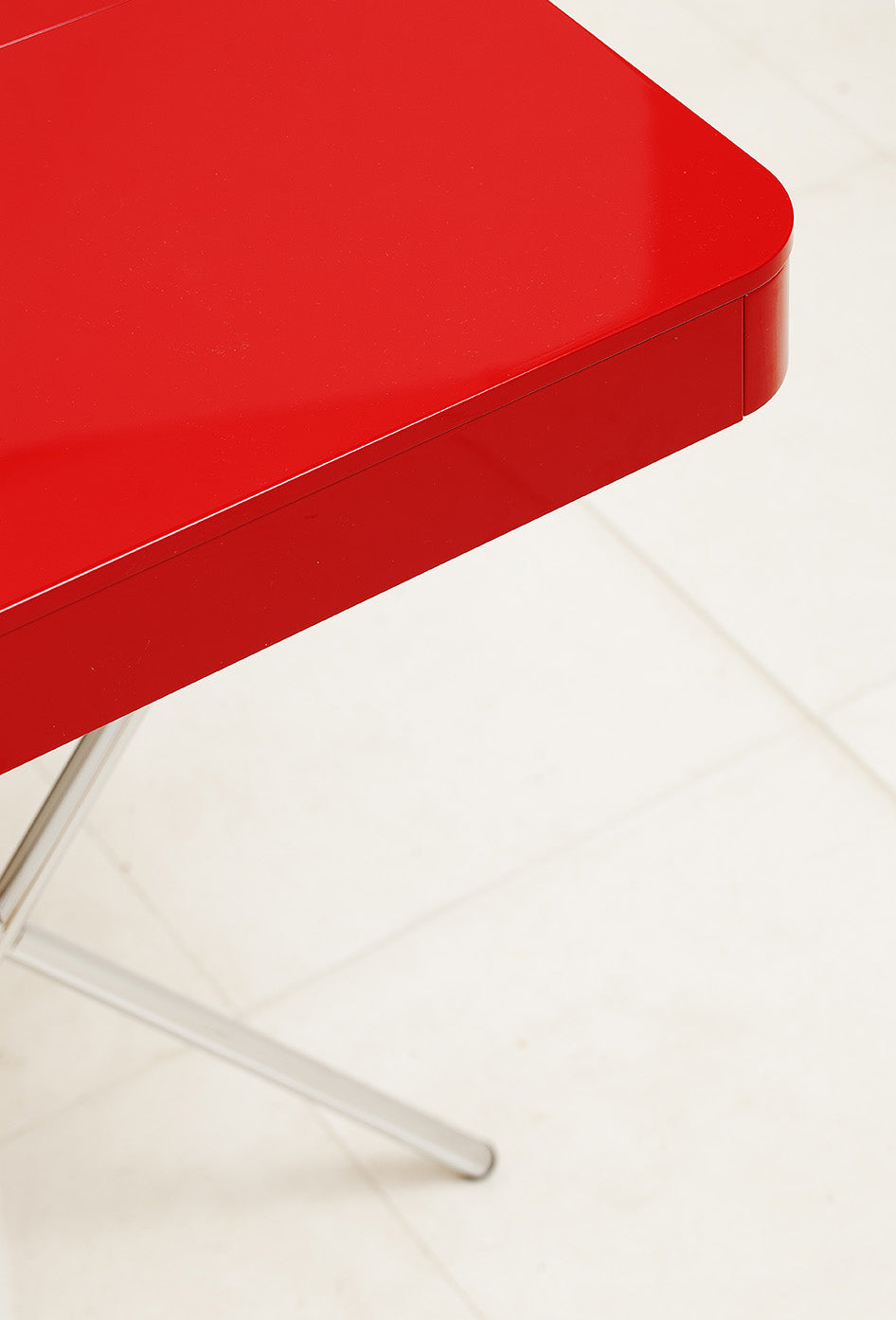 Vue plongeante sur l'angle arrondi du bureau Cosimo laqué rouge brillant