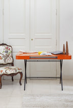 Bureau Cosimo laqué orange brillant dans un intérieur parisien, avec un fauteuil classique