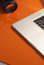 Plateau laqué orange brillant du bureau Cosimo, avec ordinateur portable et appareil photo